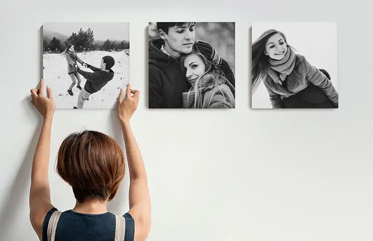 Vrouw die drie zwart-wit familiefotocanvassen ophangt